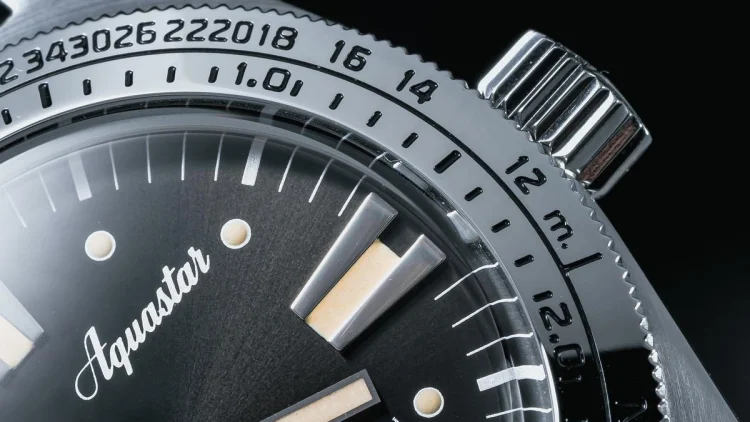 Aquastar Deepstarのベゼルとリューズのマクロショット。特許取得の減圧スケールが精緻に刻印されている。